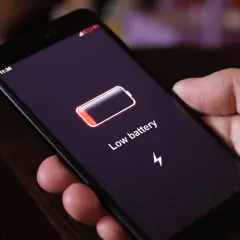 Dłoń trzyma smartfon z ikoną niskiego poziomu baterii i napisem "Low battery". Funkcja always on display pokazuje godzinę 11:30.