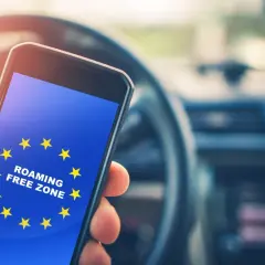 Dłoń trzyma smartfon z flagą UE i napisem "ROAMING FREE ZONE". Podróż po Europie bez dodatkowych opłat.