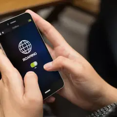 Dłoń włącza roaming na telefonie, przygotowując się do podróży po Czechach.