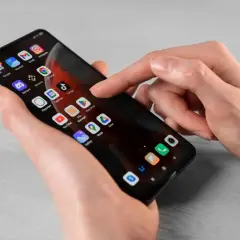 Dłoń dotyka ekranu smartfona z ikonami aplikacji. Dowiedz się, jak usunąć subskrypcję z telefonu, przeglądając ustawienia lub aplikacje.