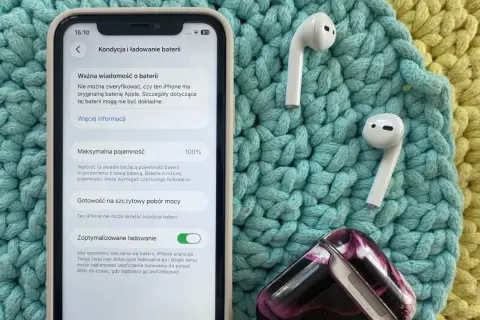 Jak sprawdzić pojemność baterii iPhone'a? Na ekranie widać 100% maksymalnej pojemności baterii, obok słuchawek AirPods.