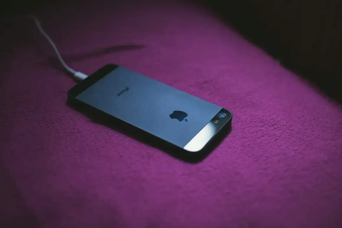 iPhone podłączony do ładowania. Dowiedz się, jak zmierzyć pojemność baterii, aby wiedzieć, jak długo telefon będzie działał.
