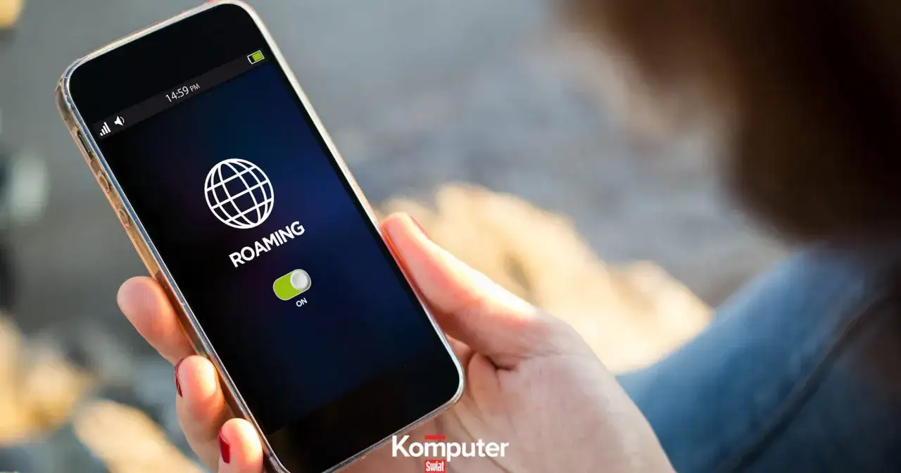 Dłoń trzyma smartfon z włączonym roamingiem, gotowa do podróży po Niemczech.